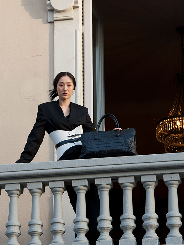 Model showcasing an elegant black leather bag, representing PK1 Milano's design and consulting services